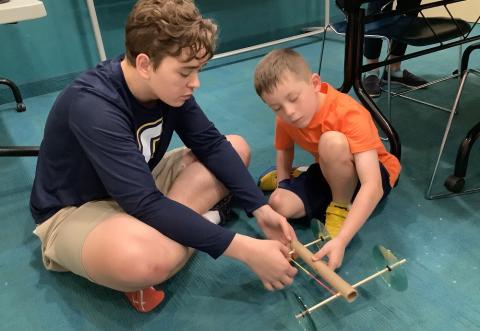 teen and young child building a moving machine
