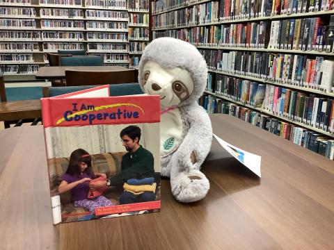Stuffed animal reading a book at the library